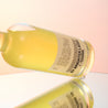 A bottle of coffee liqueur on a sunset orange gradient studio background.