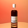 A bottle of coffee liqueur on a sunset orange gradient studio background.